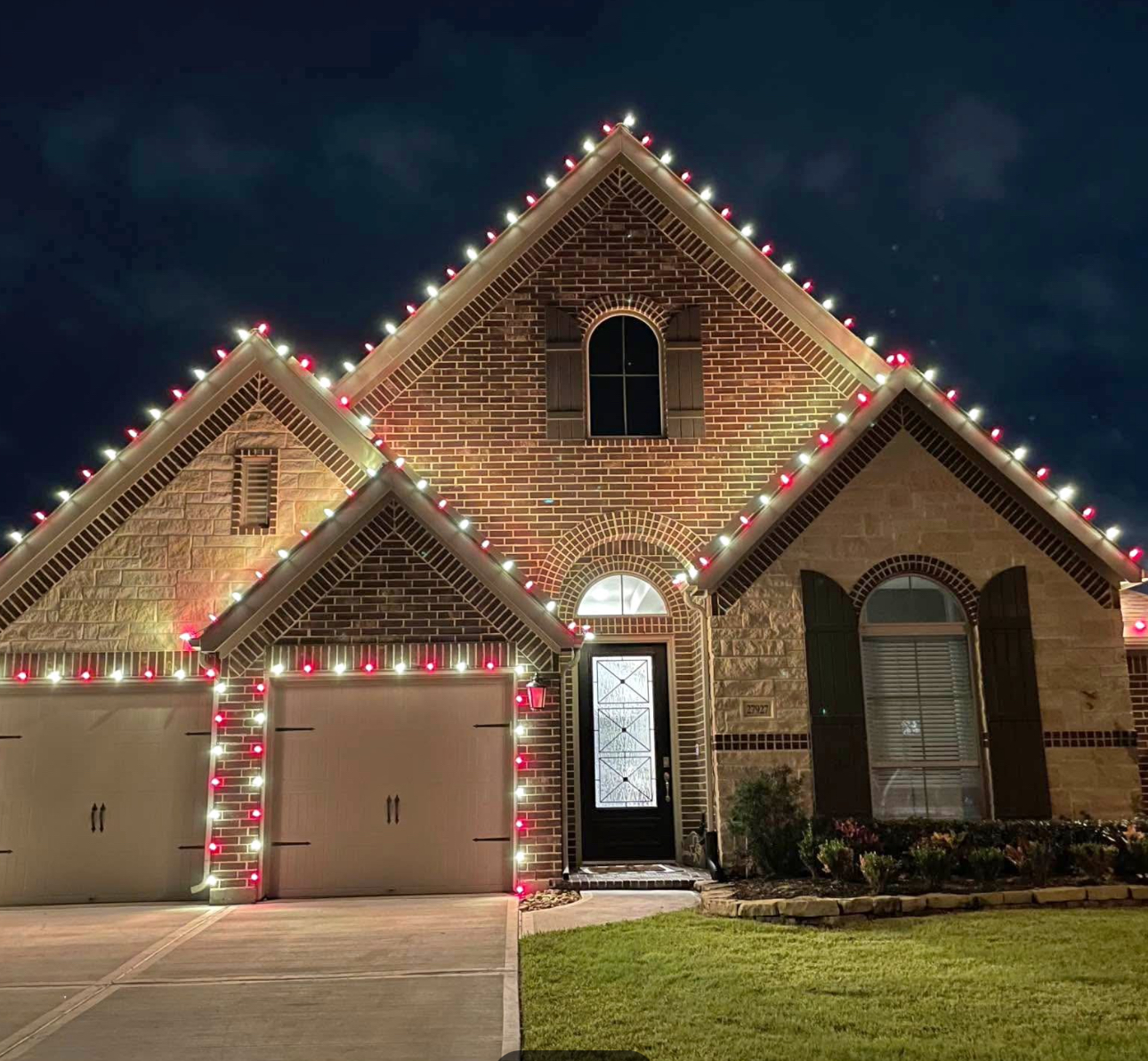 Brick home rooflines and garage outlined in red and white C9 Christmas lights