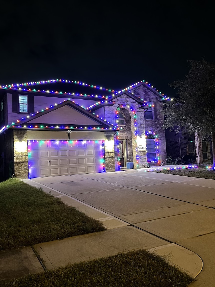 Two-story home outlined in multicolor Christmas lights